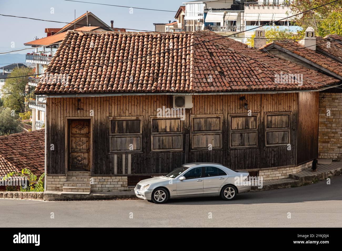 Vista sulla strada della città vecchia di Kruja Albania. Una vecchia casa con tetto in piastrelle rosse e auto parcheggiata davanti. Sito storico in Albania. Foto di viaggio, nob Foto Stock