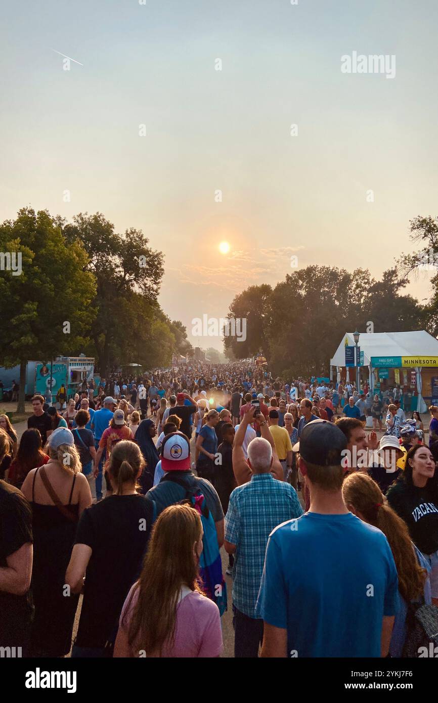 Folle di persone sotto il tramonto rosso in una fiera statale Foto Stock