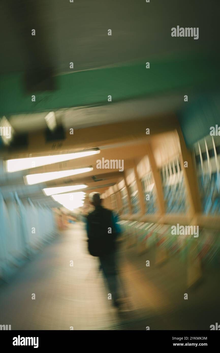 Una persona sfocata cammina in una passerella: Scattata con una velocità dell'otturatore ridotta. Una persona sfocata cammina in una passerella a Hong Kong Foto Stock