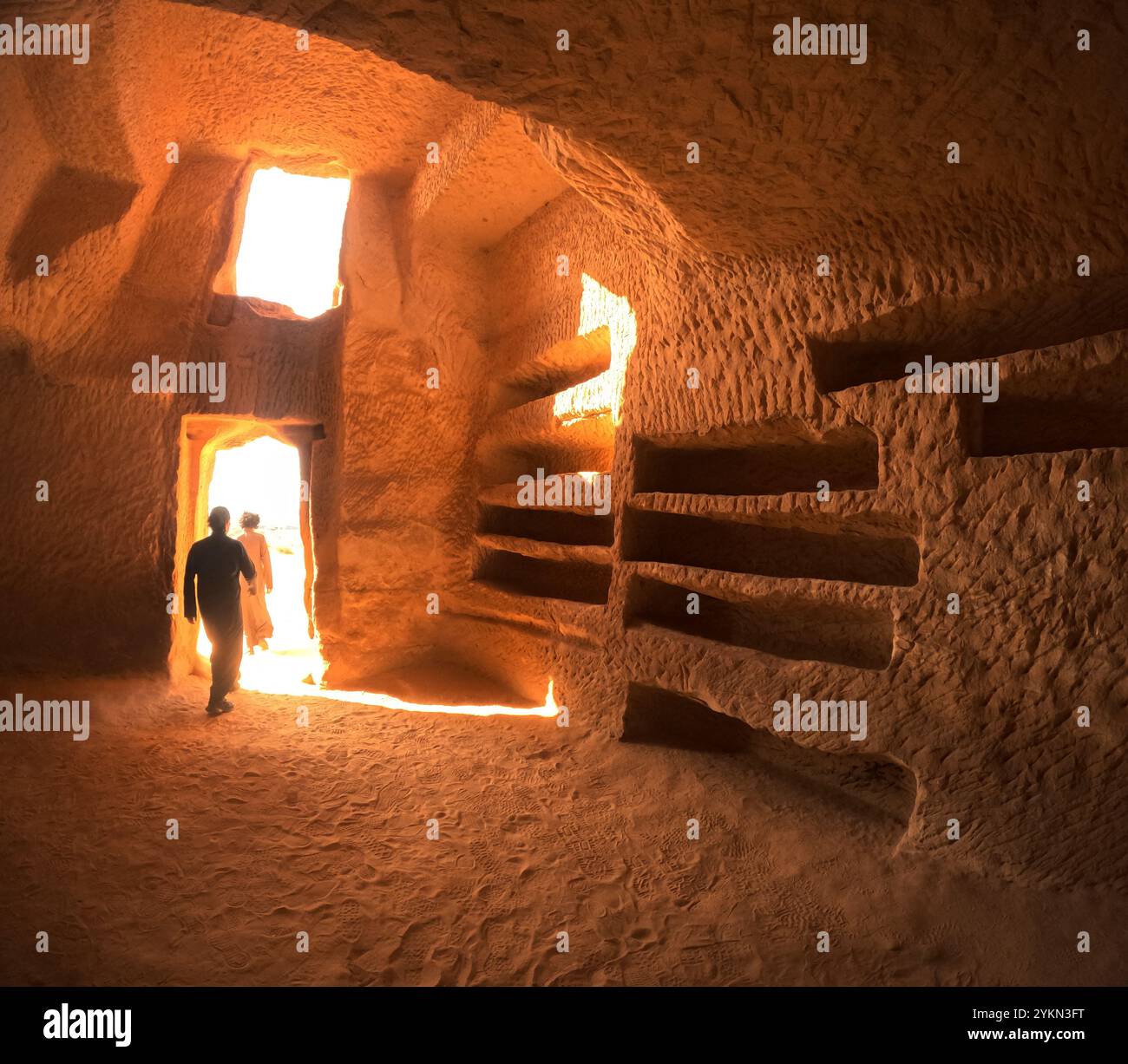 Persone che camminano fuori dalla porta della Tomba 26, Jabal AlBanat (Qasr AlBint), sito archeologico di Hegra (al-Hijr / Madā ͐ in Ṣāliḥ), nel deserto vicino ad al Ula, Foto Stock