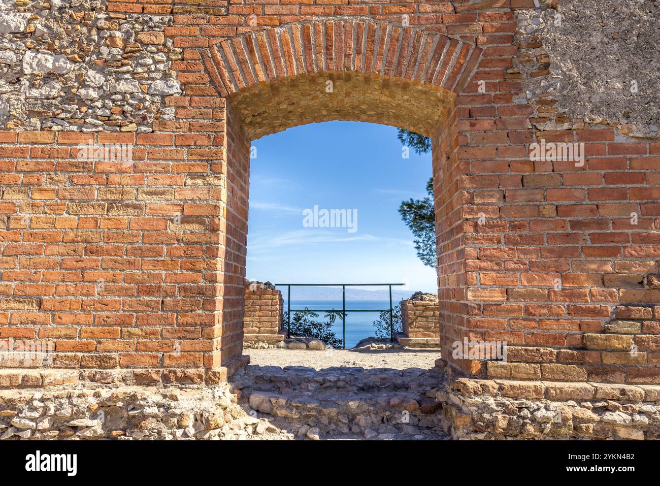 Un muro di mattoni con un passaggio che conduce al mar mediterraneo Foto Stock