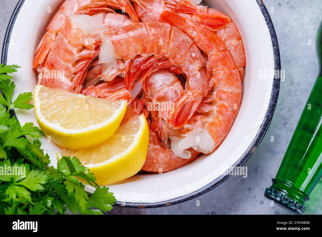 Gamberetti crudi freschi, accompagnati da rametti di prezzemolo fresco e limone succoso, pronti per la cottura. Spuntino con birra ideale Foto Stock