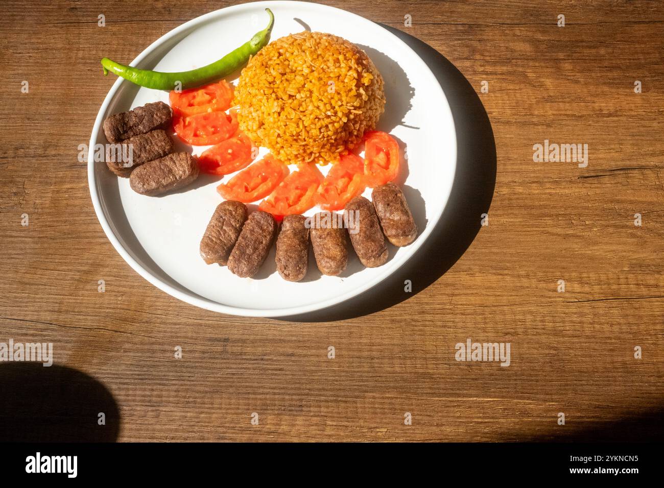 Un tradizionale piatto balcanico di polpette cevapi su un tavolo di legno in primo piano Foto Stock