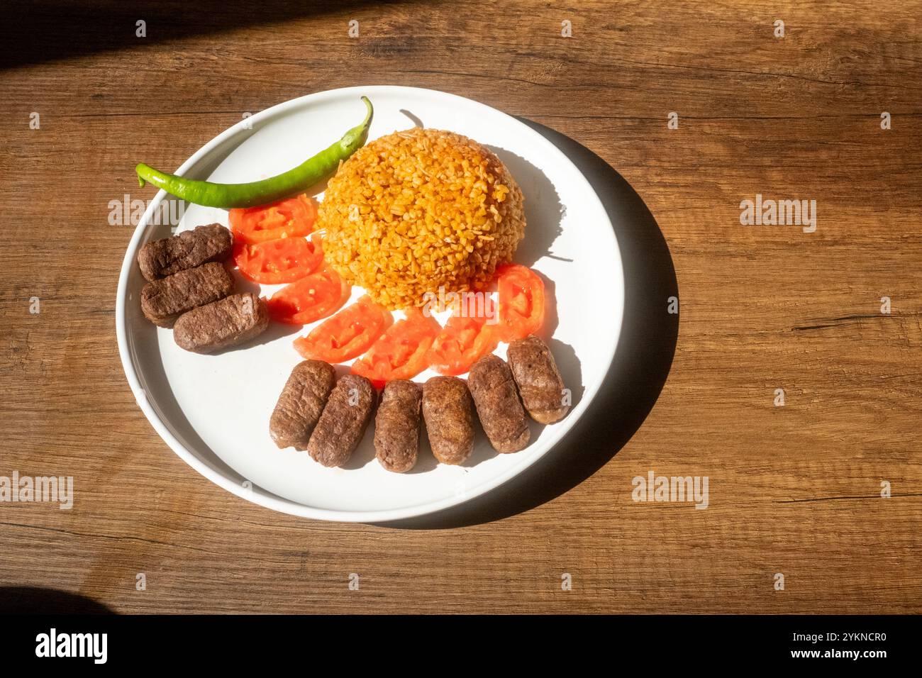 Un tradizionale piatto balcanico di polpette cevapi su un tavolo di legno in primo piano Foto Stock