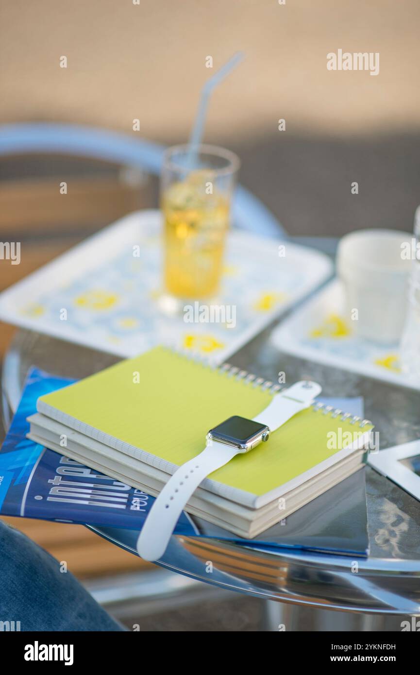 Libri di testo e orologi indossabili sul tavolo Foto Stock