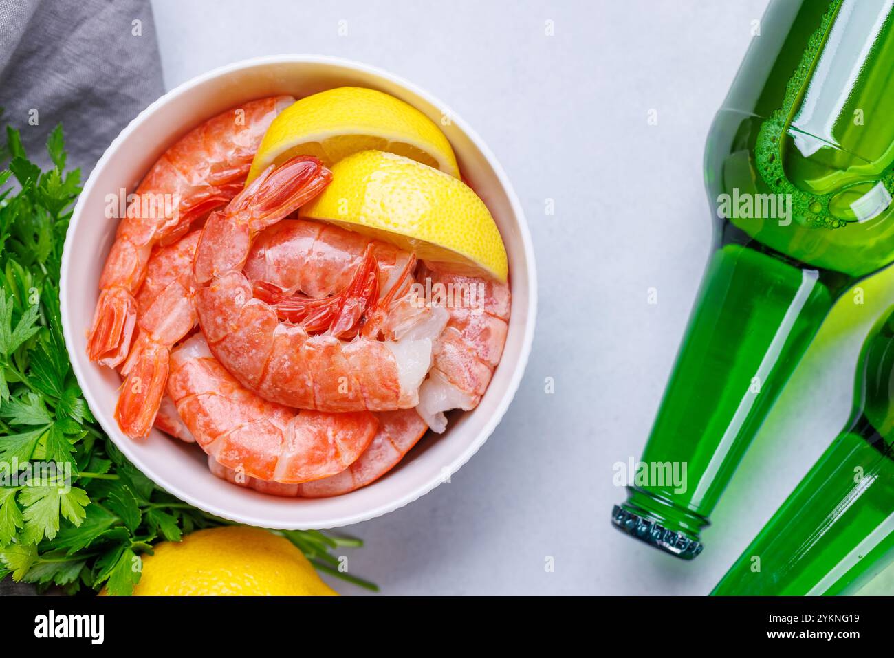 Gamberetti crudi freschi, accompagnati da rametti di prezzemolo fresco e limone succoso, pronti per la cottura. Spuntino con birra ideale Foto Stock