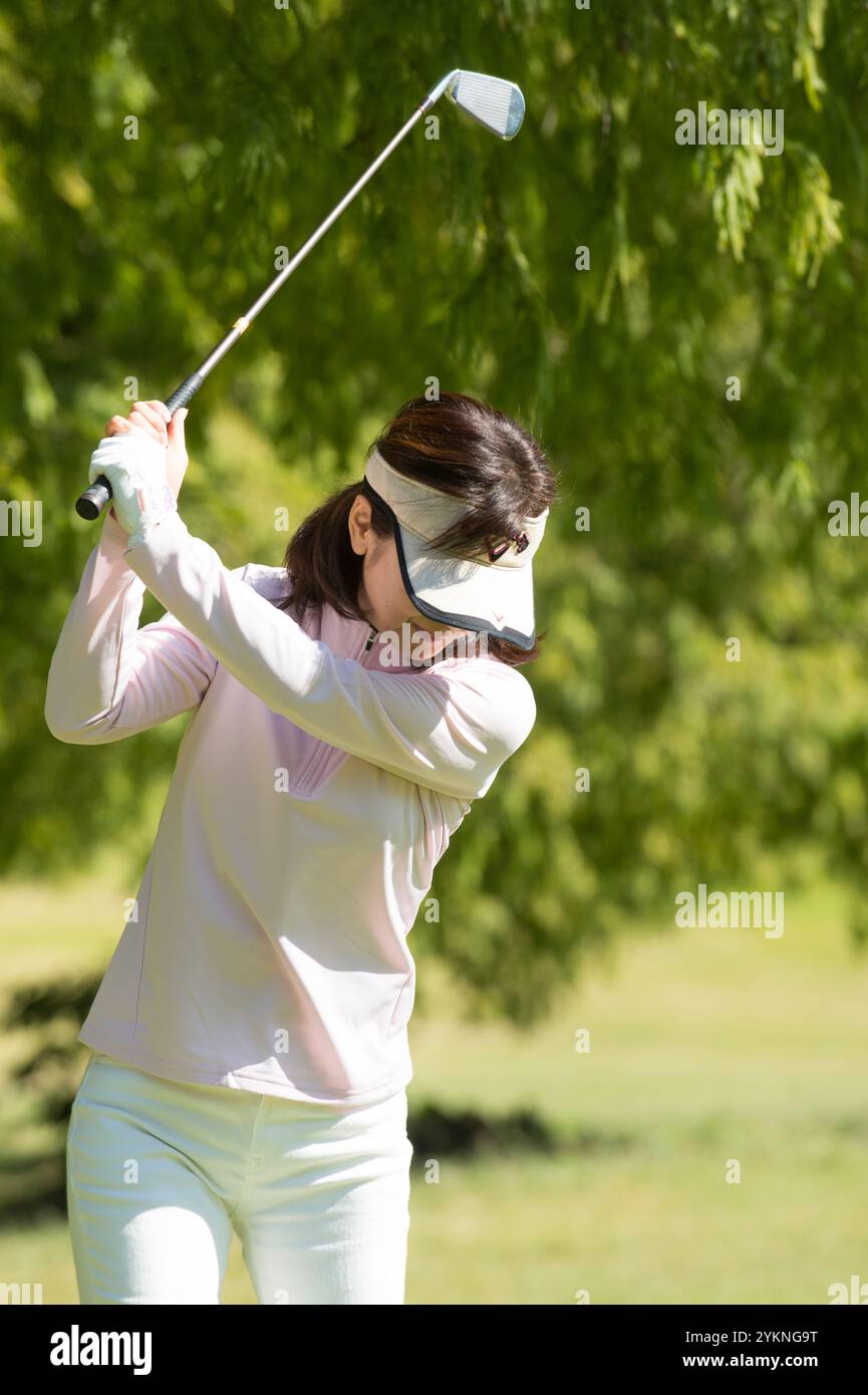 Donna di mezza età che gioca a golf Foto Stock