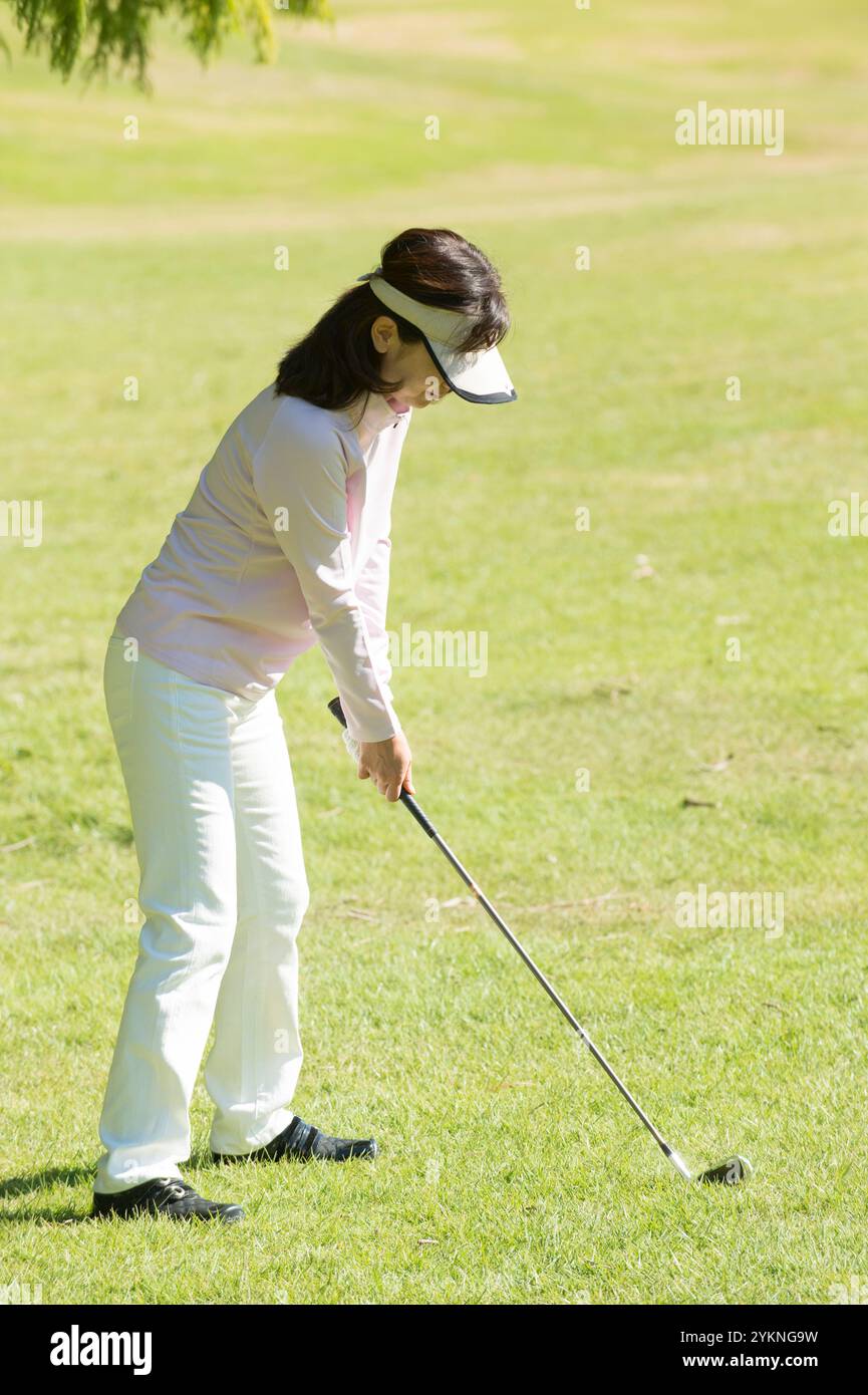 Donna di mezza età che gioca a golf Foto Stock