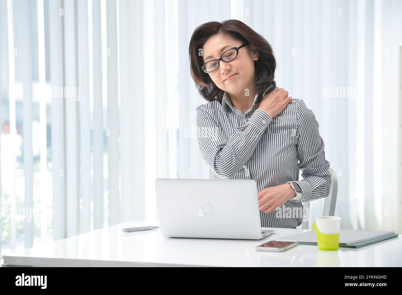 Donna d'affari con spalle rigide dal lavoro sulla scrivania Foto Stock