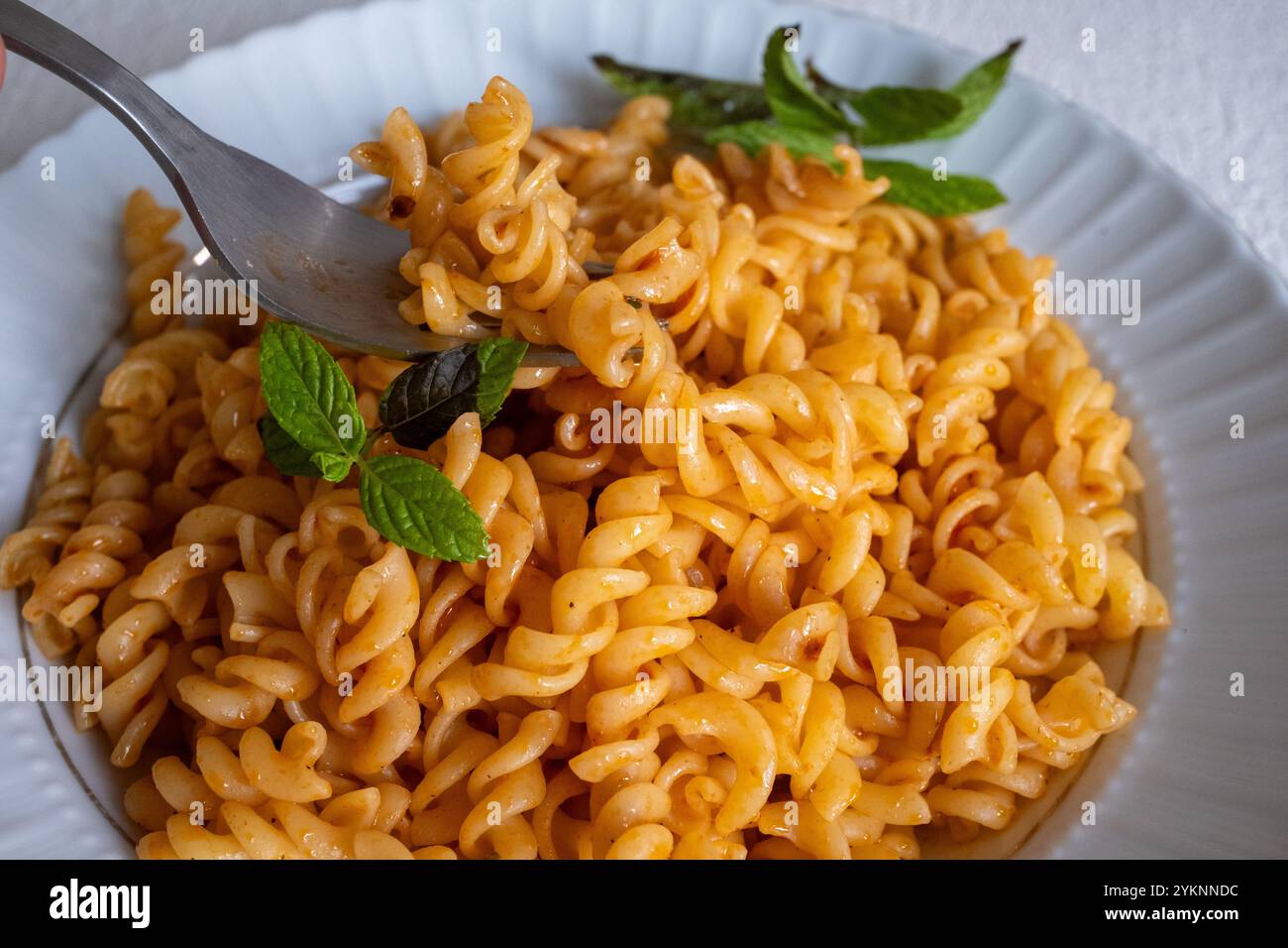 pasta a spirale con salsa di pomodoro cremosa su un piatto bianco al rallentatore Foto Stock