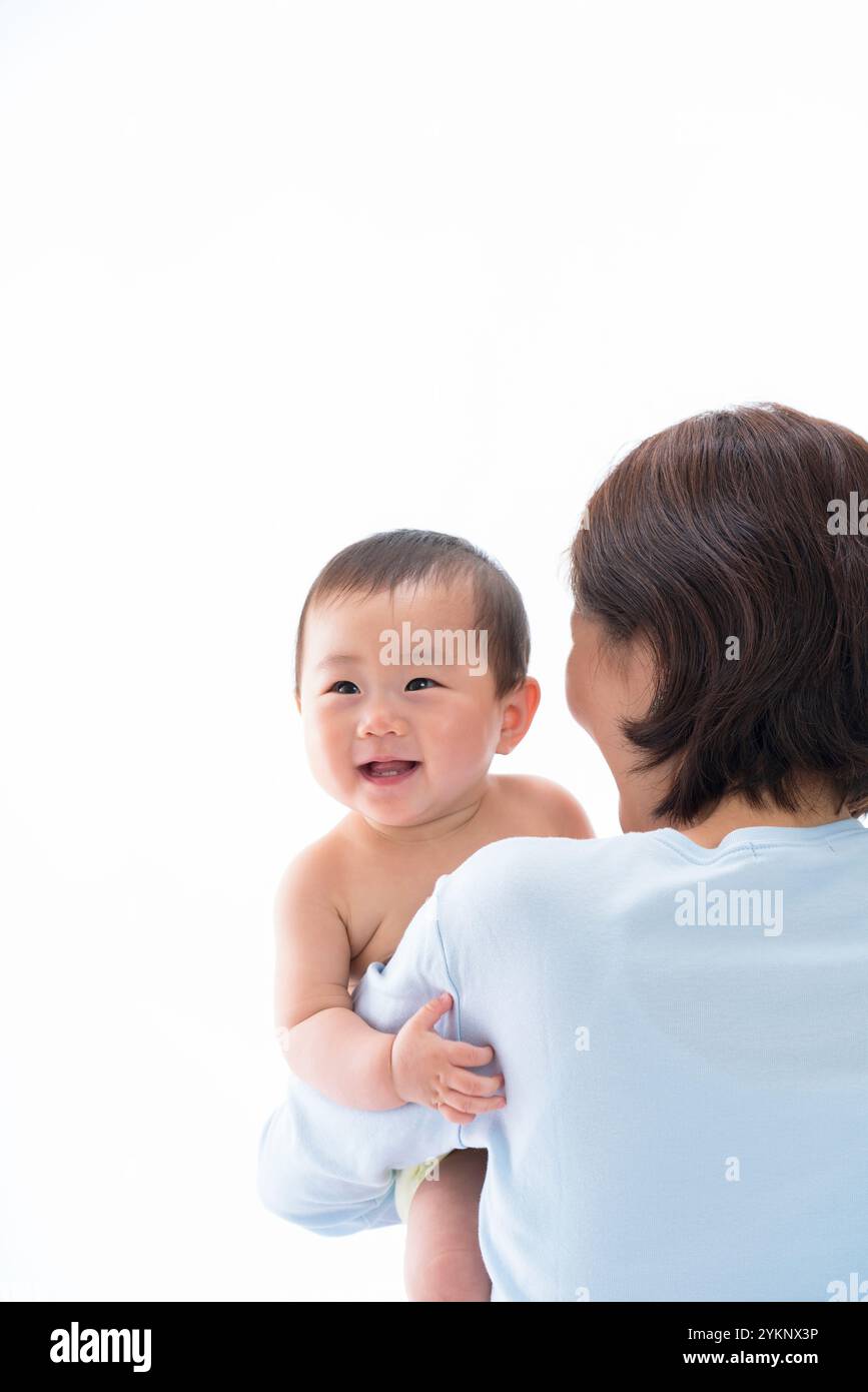 Il bambino sorride dalla spalla della mamma. Foto Stock