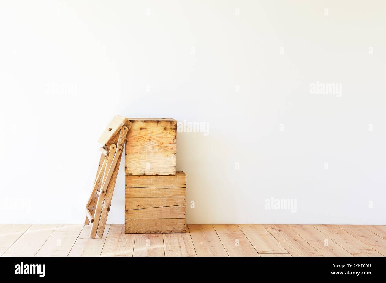 Pavimento in legno, parete bianca, scatola per vini e scala a cavalletto Foto Stock