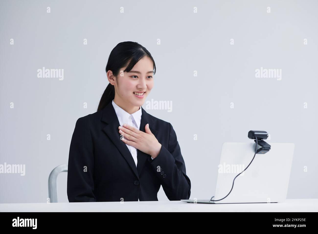 Giovane donna in tuta che parla con la fotocamera davanti al laptop Foto Stock