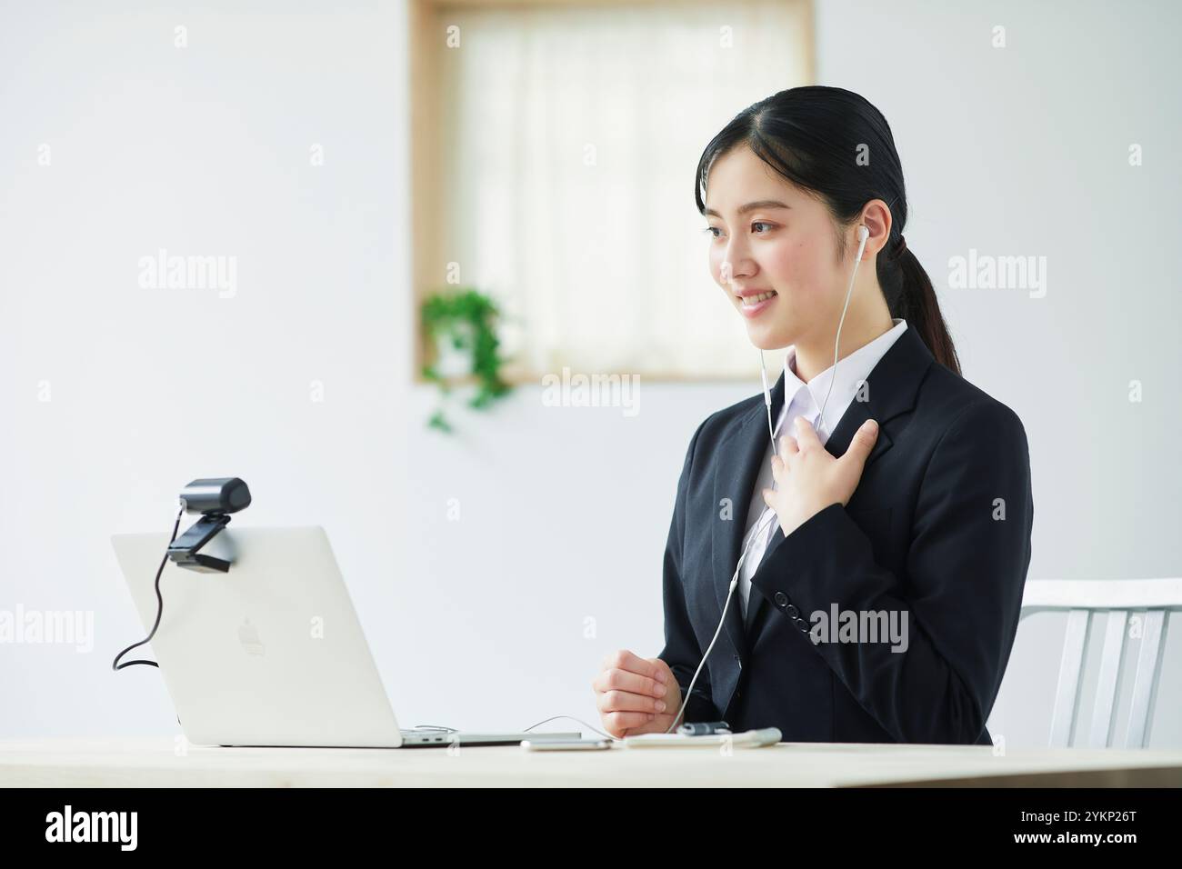 Giovane donna in tuta che parla con la fotocamera davanti al laptop Foto Stock