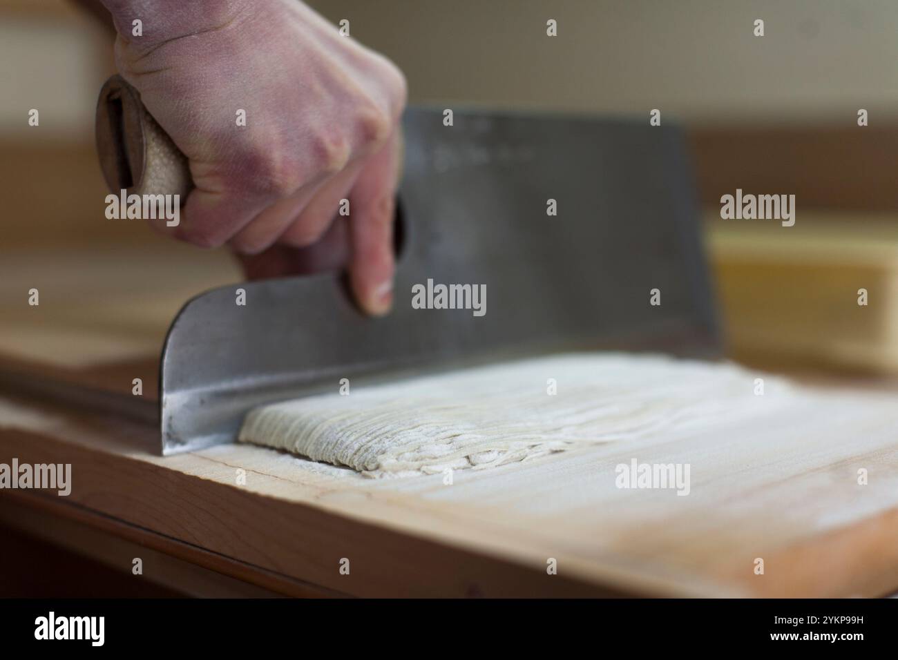 Mano di un artigiano che taglia l'impasto di grano saraceno con un coltello Foto Stock