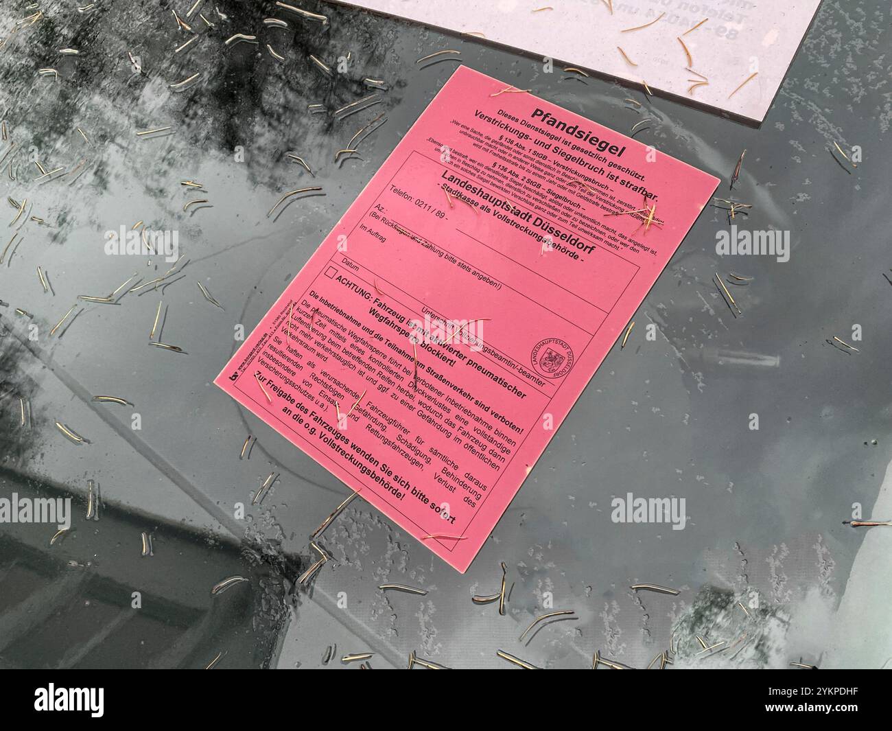 Gepfändet! Siegel und Aufkleber auf einem Auto a Düsseldorf. Der rote Punkt an stelle des Stadtsiegels macht die Stilllegung sofort sichtbar. Foto Stock