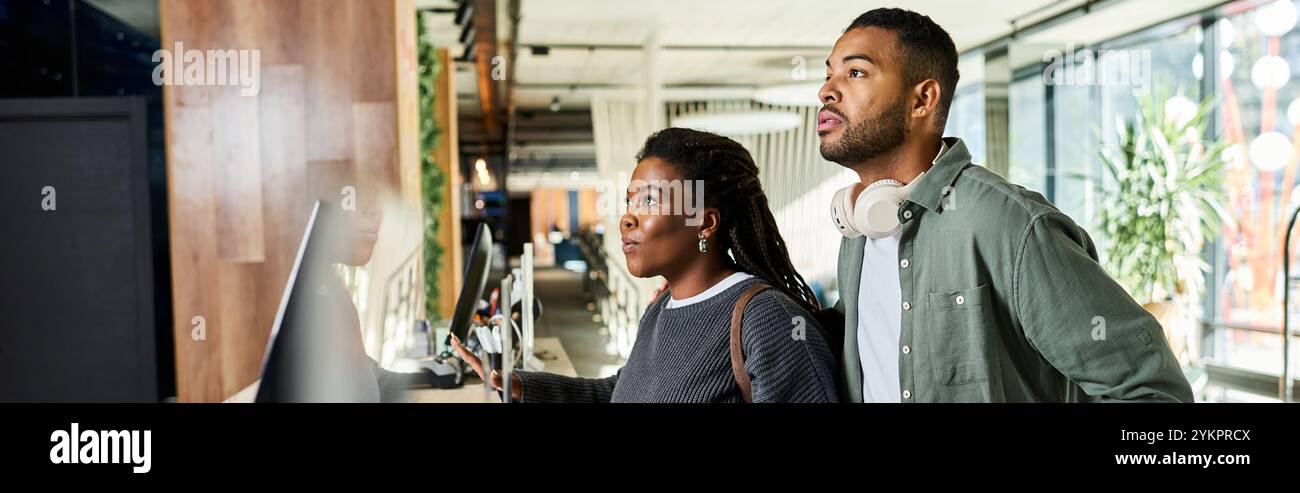 Una giovane coppia afro-americana si trova con attenzione alla reception dell'hotel, eccitata per la loro vacanza. Foto Stock