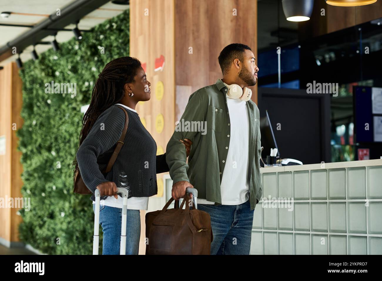 Una giovane coppia afroamericana si trova alla reception dell'hotel, iniziando eccitatamente il loro viaggio di vacanza. Foto Stock