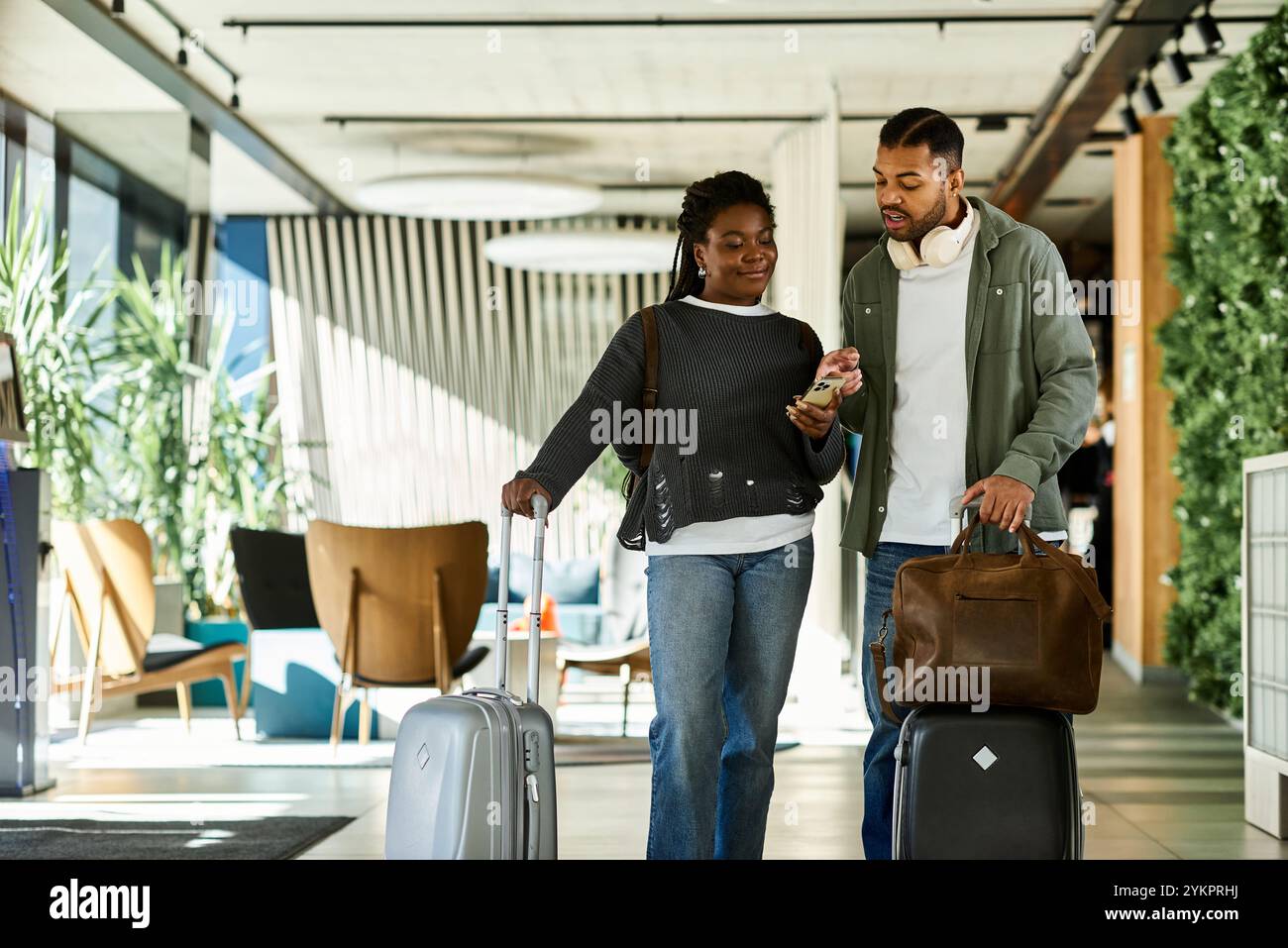 Una giovane coppia esplora un'elegante hall dell'hotel, eccitata per le loro avventure di vacanza. Foto Stock