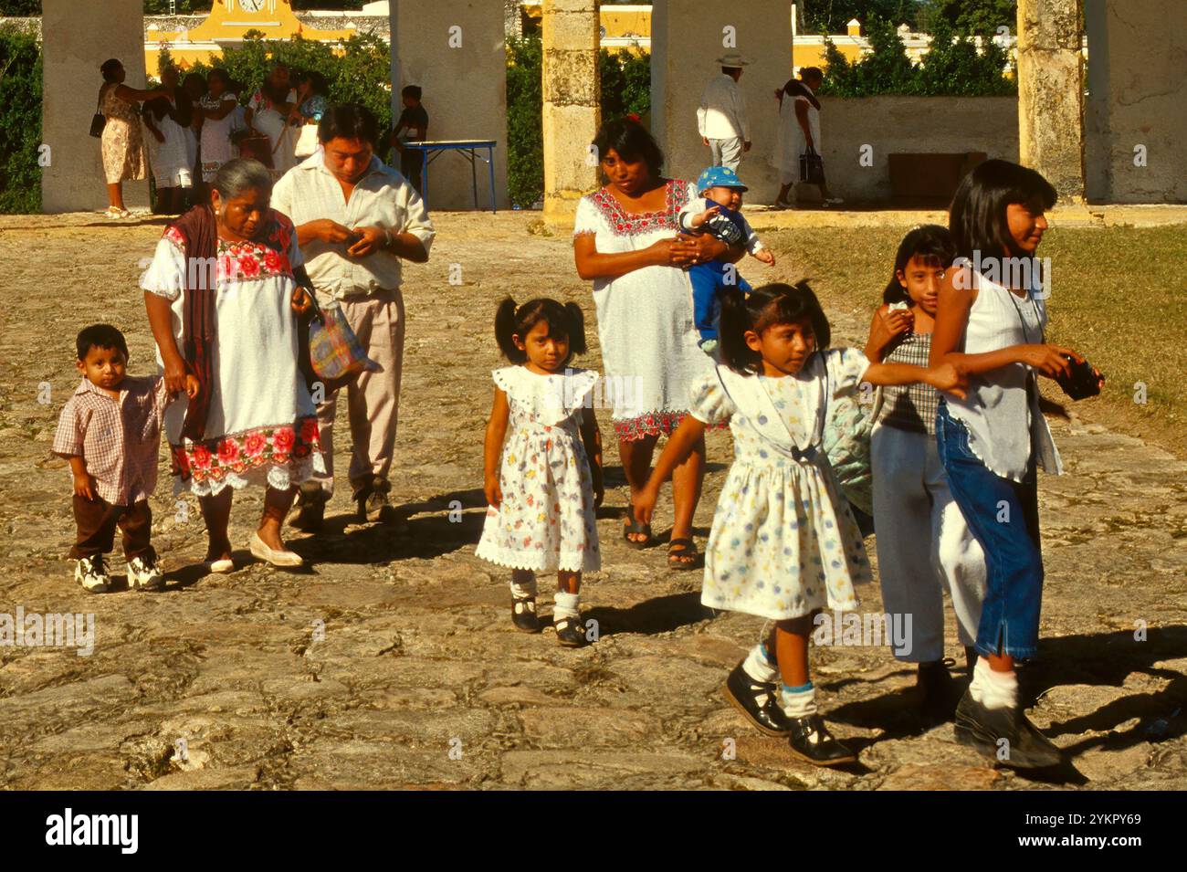 Famiglia Maya in viaggio per partecipare alla messa, donne che indossano abiti huipil, atrio al Convento de San Antonio de Padova, Izamal, Yucatan, Messico Foto Stock