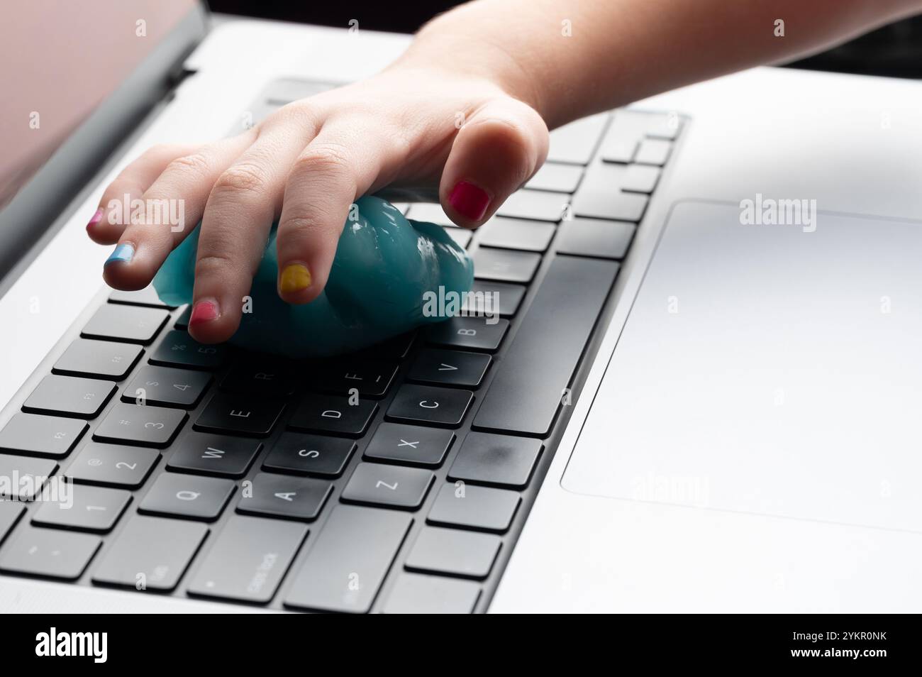 Mano con unghie colorate che puliscono la tastiera del laptop vista ravvicinata Foto Stock