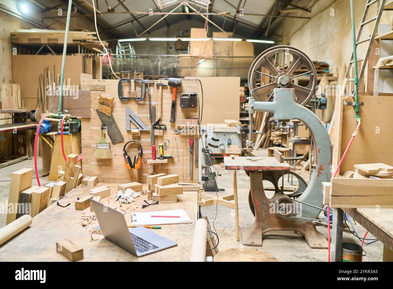 Un'animata officina di legno piena di attrezzi e macchinari in un bosco, che mette in mostra la maestria artigianale e gli spazi di lavoro manuali, pronti per progetti creativi Foto Stock