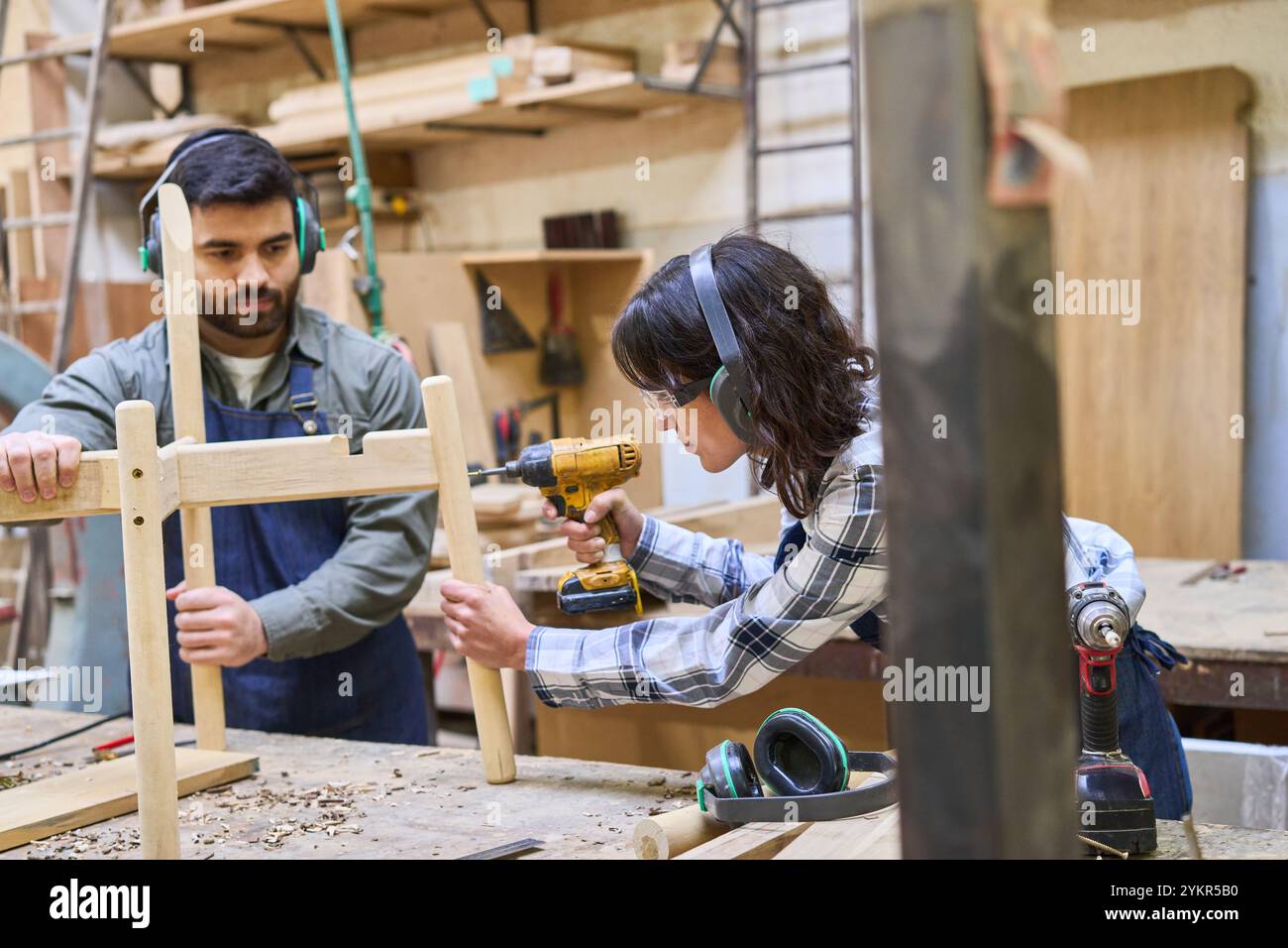 Un giovane apprendista collabora con un mentore esperto in un bosco, concentrandosi sul lavoro di squadra e sull'allenamento pratico. La scena enfatizza l'artigiano Foto Stock