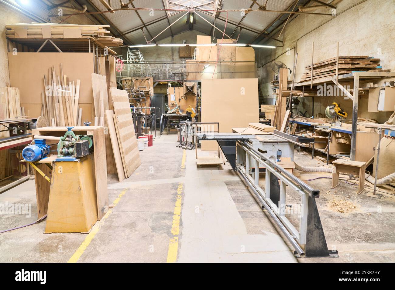 Un'ampia officina in legno con varie macchine e materiali per la lavorazione del legno, che presenta uno spazio organizzato per le attività di falegnameria. Ambiente perfetto Foto Stock