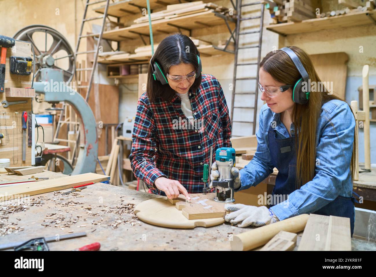 Giovane apprendista che impara le capacità di lavorazione del legno da un mentore esperto in un ambiente vivace. La scena mostra il lavoro di squadra e l'artigiano Foto Stock