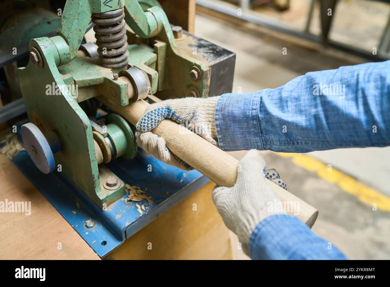 Una visione dettagliata delle mani di un lavoratore che aziona macchinari, modellando il legno in un bosco. L'immagine mette in evidenza l'artigianalità e il processo industriale, emph Foto Stock