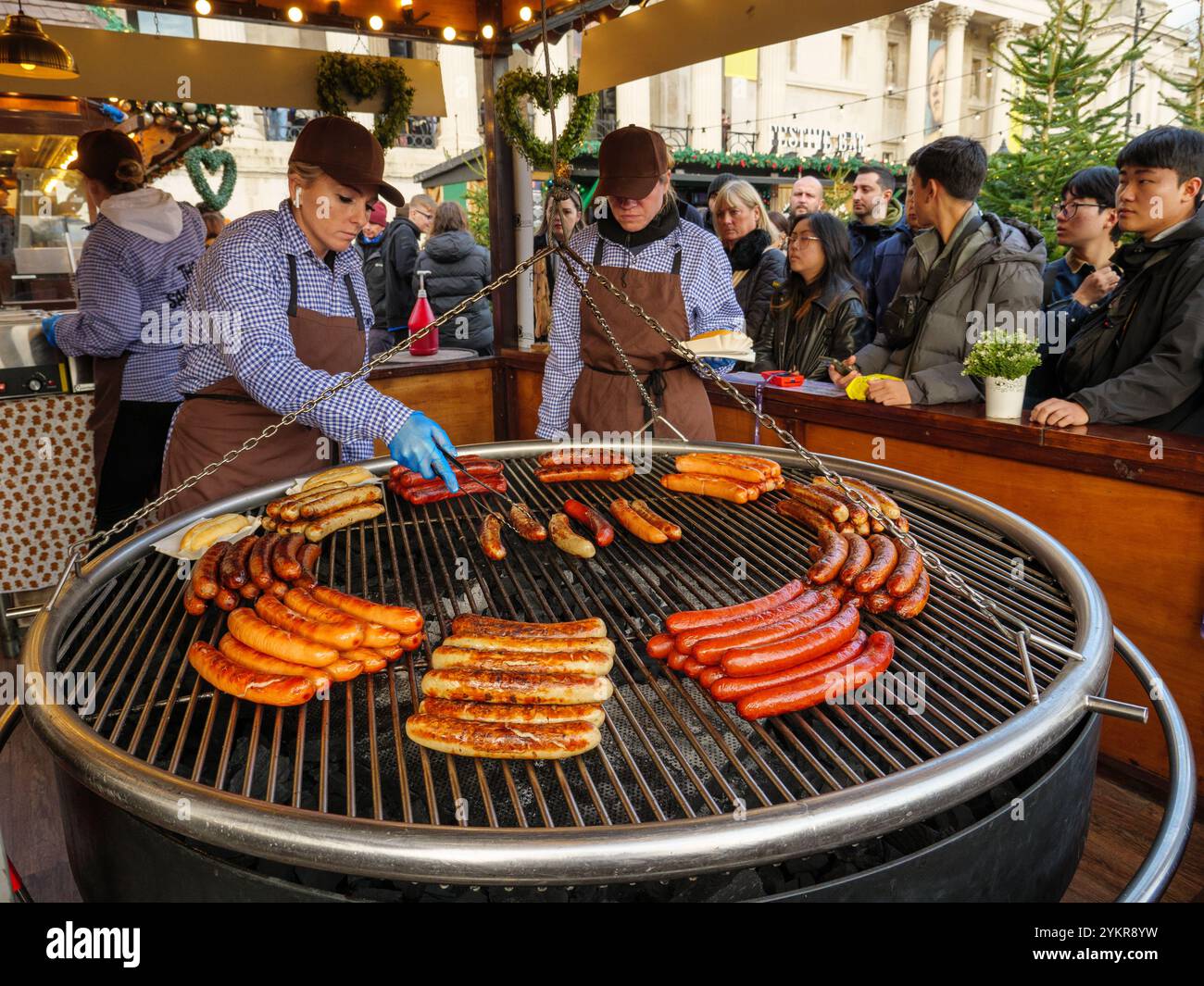 Salsicce bratwurst grigliate presso il chiosco di cibo della German Sausage Company al mercatino di Natale di Trafalgar Square, Londra, Regno Unito Foto Stock