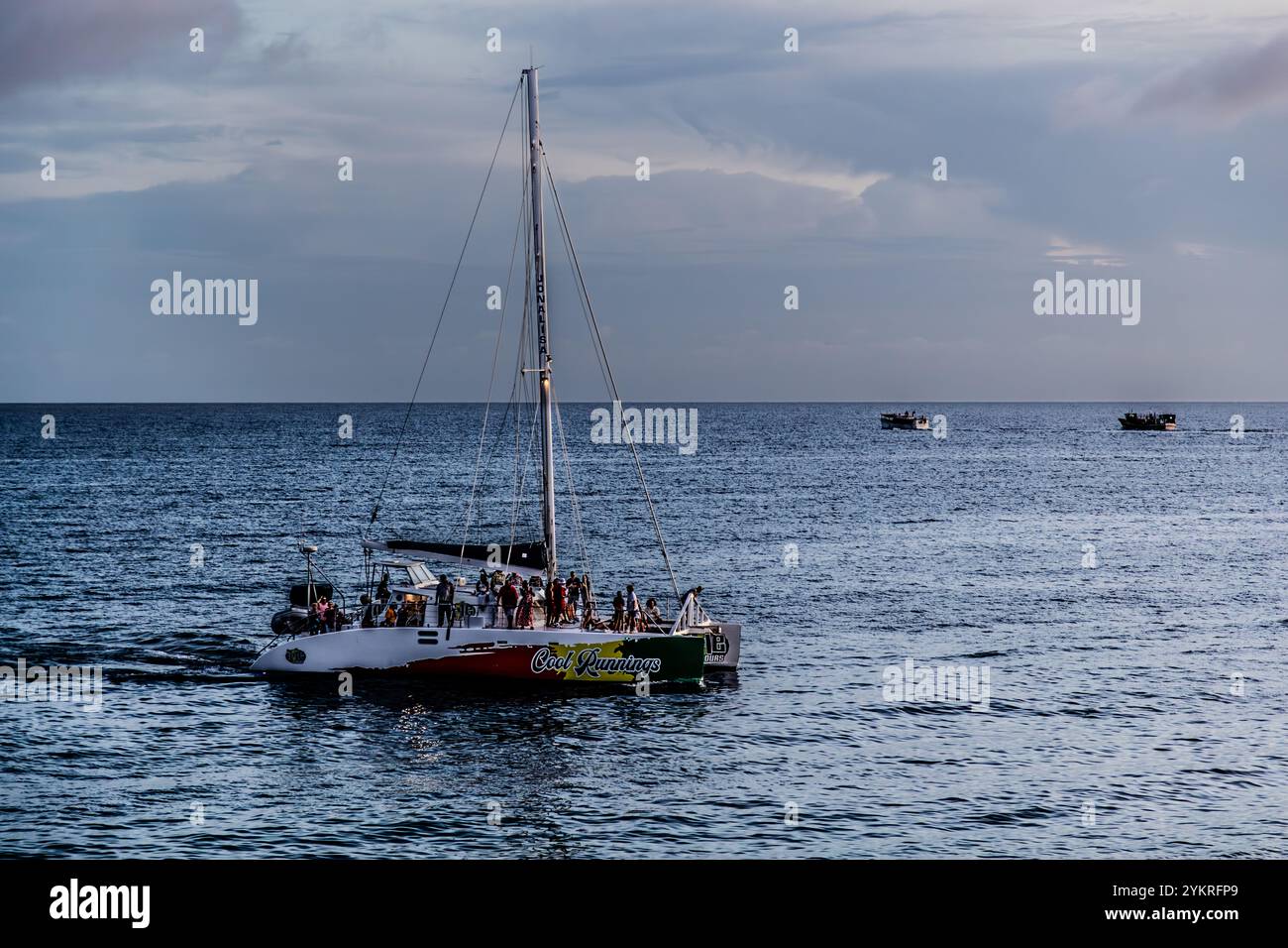 Atmosfera serale sull'oceano sulla costa meridionale di Curacao. Un catamarano con turisti giornalieri torna dalla sua gita di un giorno a Willemstad e sullo sfondo potrai vedere le barche dei venditori di frutta e verdura venezuelani che tornano in Venezuela dal mercato galleggiante di Willemstad. Kaya Wilson Godett, Curacao, Curacao, Kòrsou Foto Stock