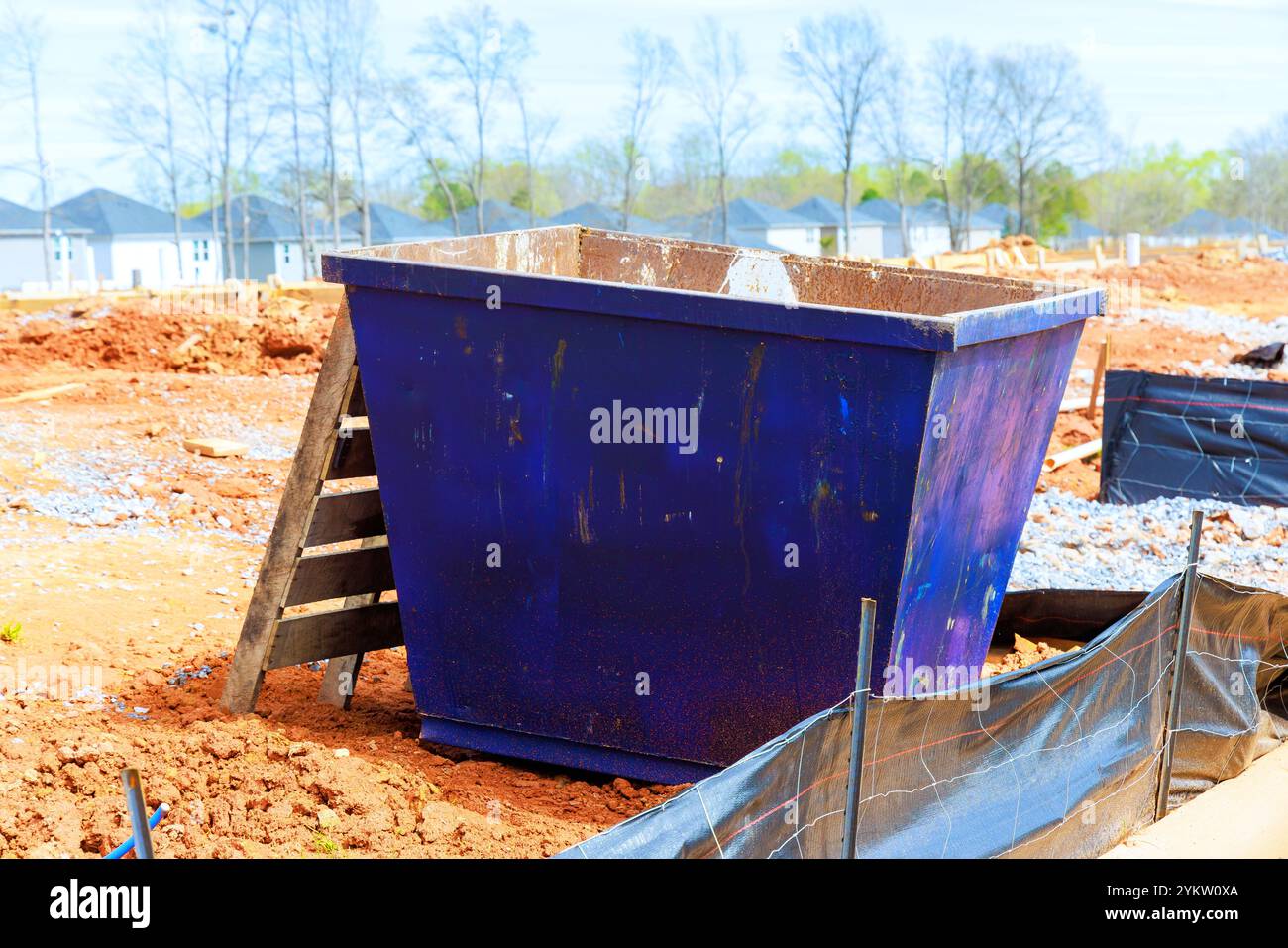 Il cassonetto è posizionato nel cantiere, circondato da tumuli di sterrato in fase di costruzione di nuove case Foto Stock