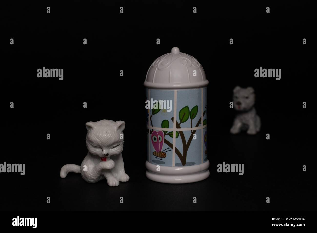 Gatto bianco con piccolo cane seduto vicino alla colonna morris, giocattolo pubblicitario in plastica Foto Stock