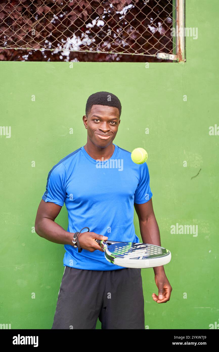 Ritratto di un giocatore di paddle tennis africano con racchetta isolata su sfondo verde. Foto Stock