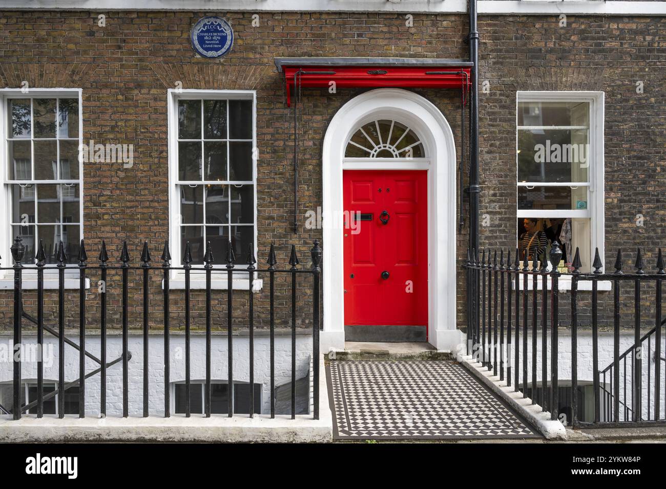 Porta d'ingresso rossa in un edificio in mattoni con recinzione in ghisa, Charles Dickens Museum, 48-49 Doughty Street, Holborn, London Borough of Camden, Inghilterra Foto Stock