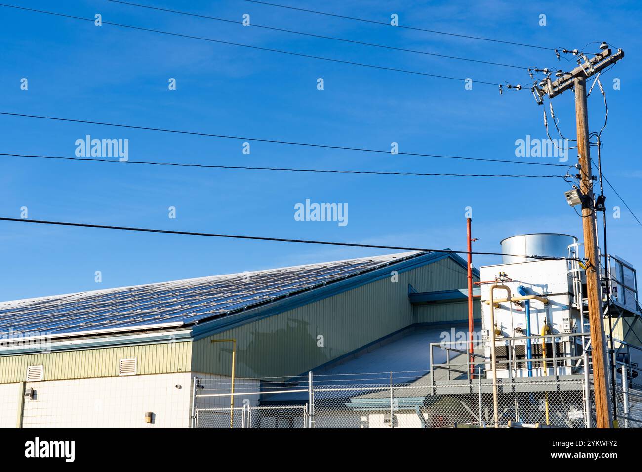 Pannelli solari con paraspruzzi che generano energia con linee elettriche e attrezzature per la produzione del ghiaccio presso un centro locale e una pista di hockey a Calgary Albert Foto Stock