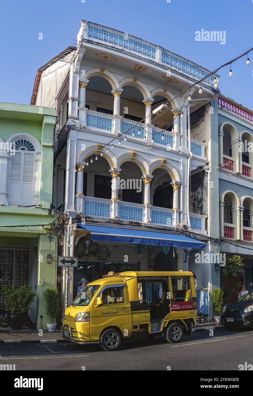 Una foto di un tuk tuk giallo di fronte alla colorata architettura cino portoghese nella città vecchia di Phuket Foto Stock