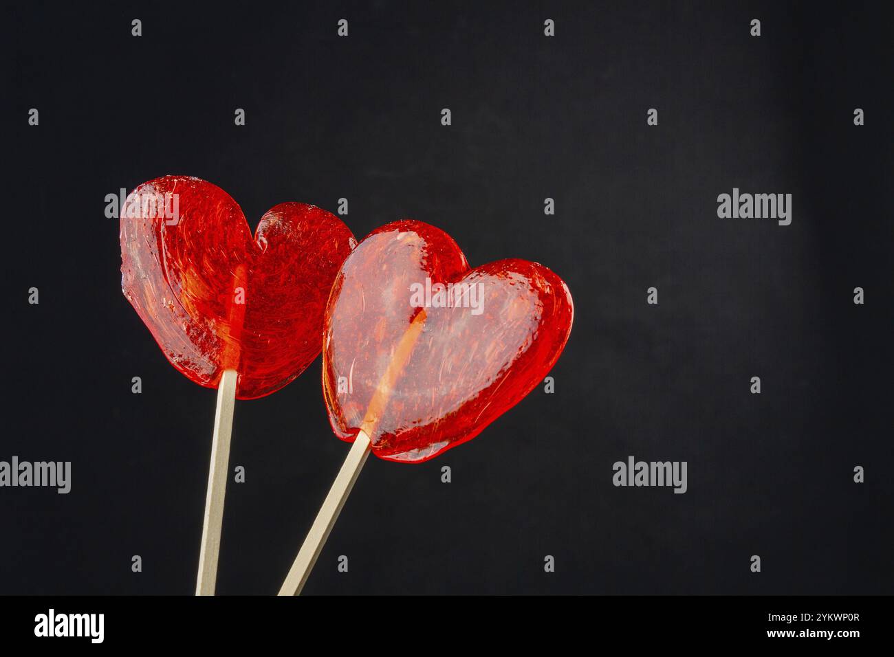 Due caramelle lecca-lecca rosse e spazio di copia. Isolato sul nero Foto Stock