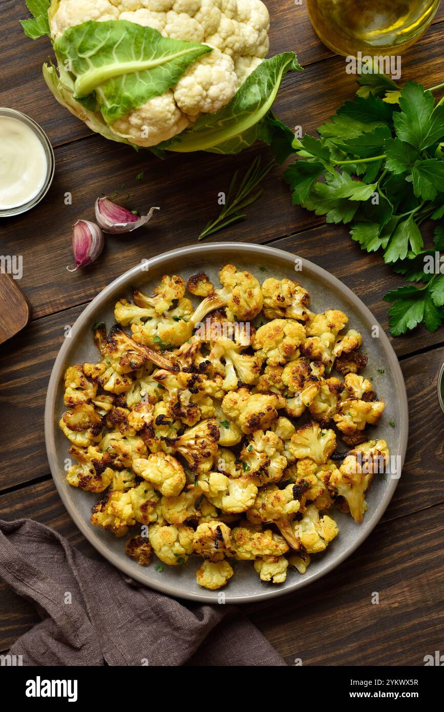 Cavolfiore arrosto su tavola di legno. Cucina vegetariana vegana. Vista dall'alto, disposizione piatta Foto Stock