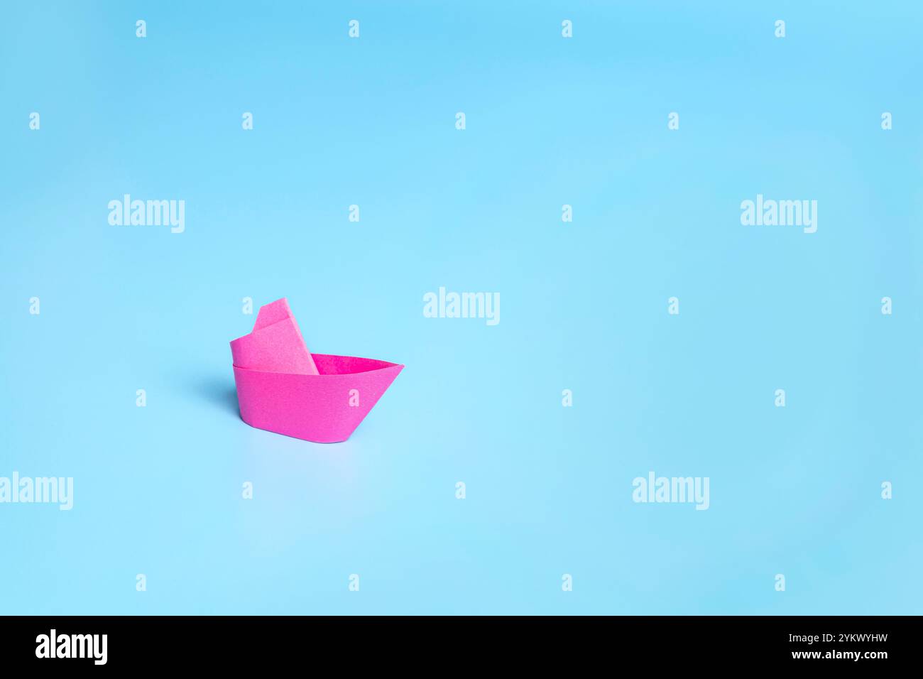 Una barca rossa solitaria su sfondo blu che simboleggia il mare. Foto Stock