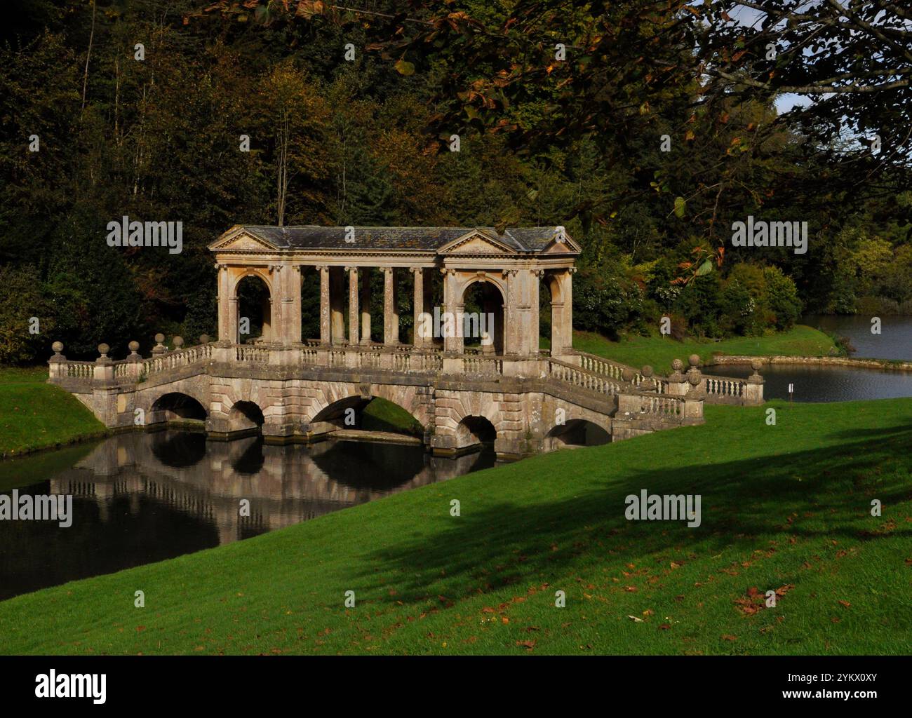 Il ponte palladiano, sotto il sole autunnale, sul lago nei giardini del Priory Park di Bath. Progettato nel XVIII secolo da Alexander Pope e landsca Foto Stock