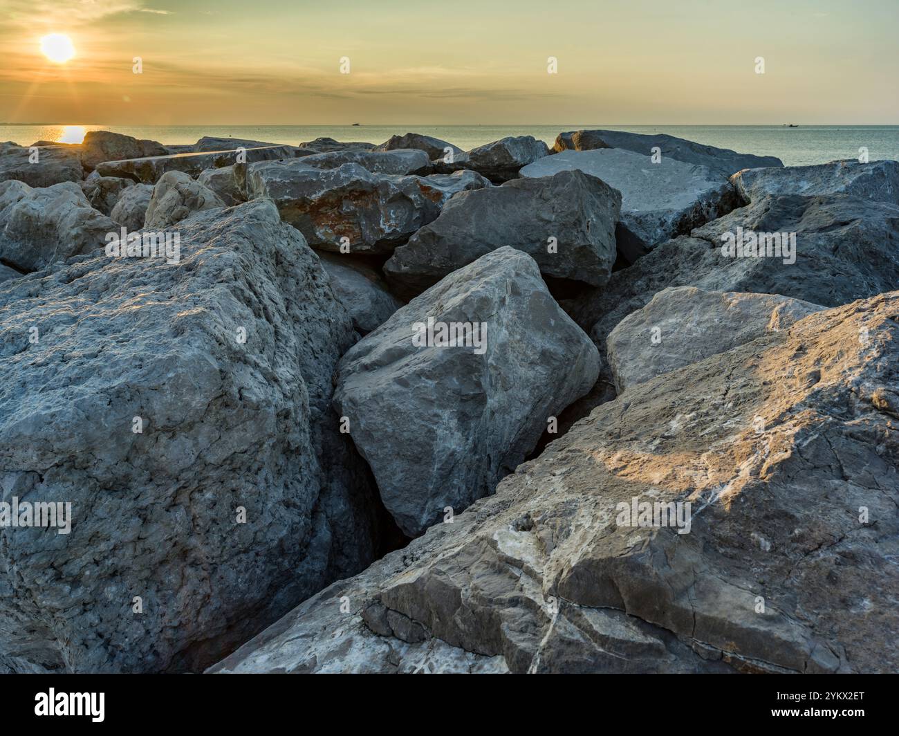 Paesaggio con scogli sulla spiaggia di Caorle in Italia, con colori dell'alba Foto Stock