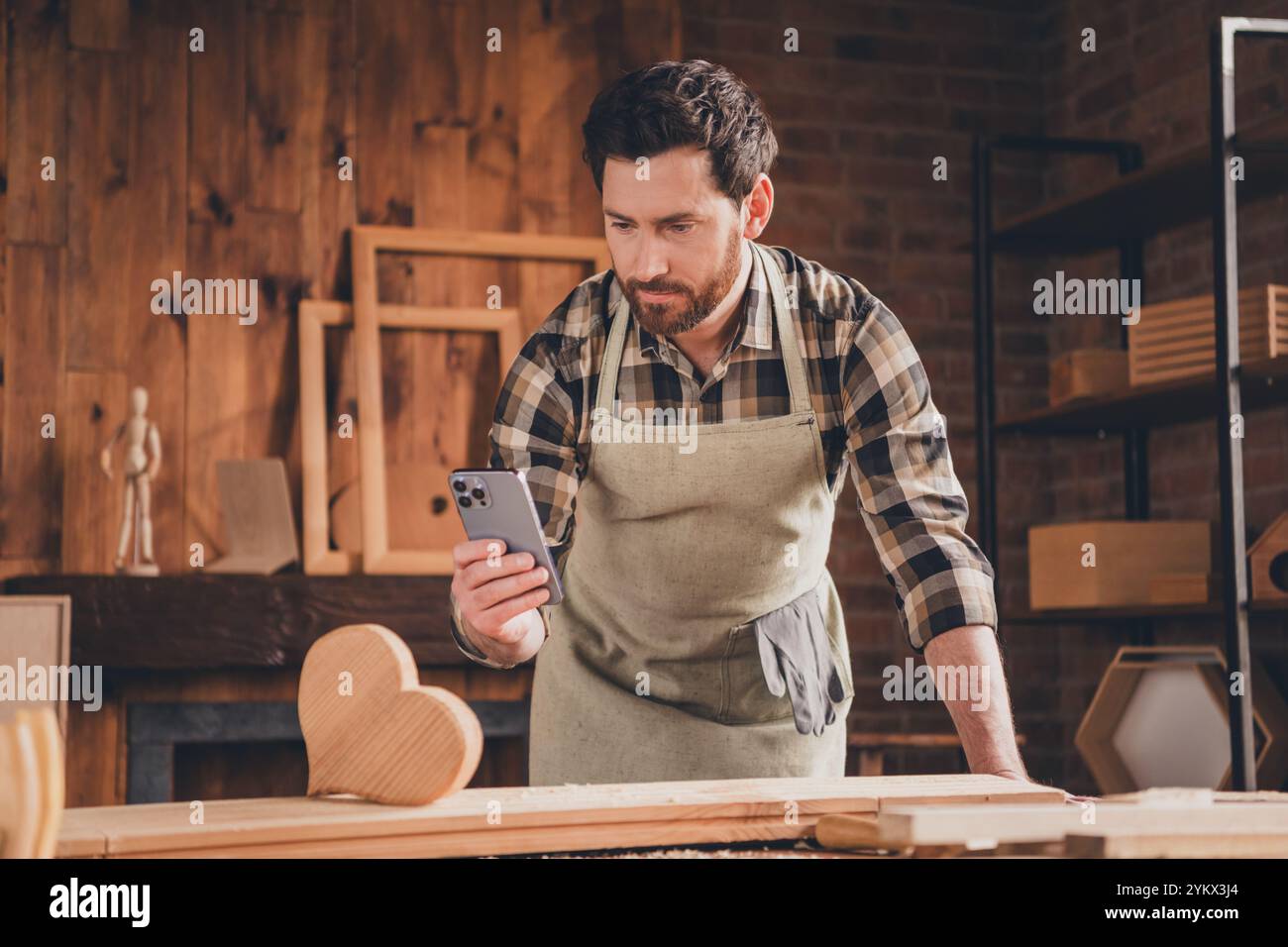 Foto di un ragazzo che fotografa su cellulare gadget intelligente cuore di legno in officina Foto Stock