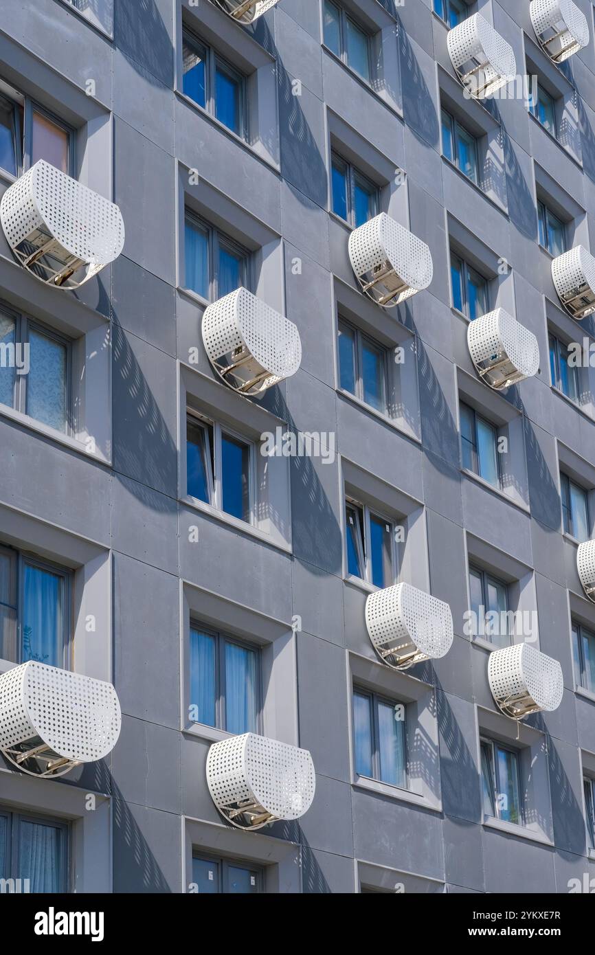 Facciata di un edificio residenziale con file di finestre e involucro protettivo esterno per unità di aria condizionata Foto Stock