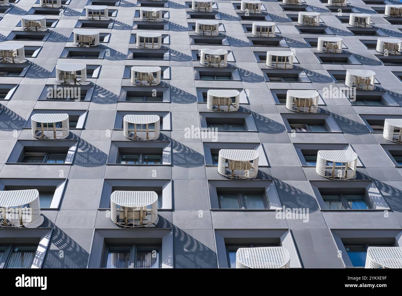 Schema geometrico della facciata di un condominio residenziale con file di finestre e involucro protettivo esterno per le unità di aria condizionata Foto Stock