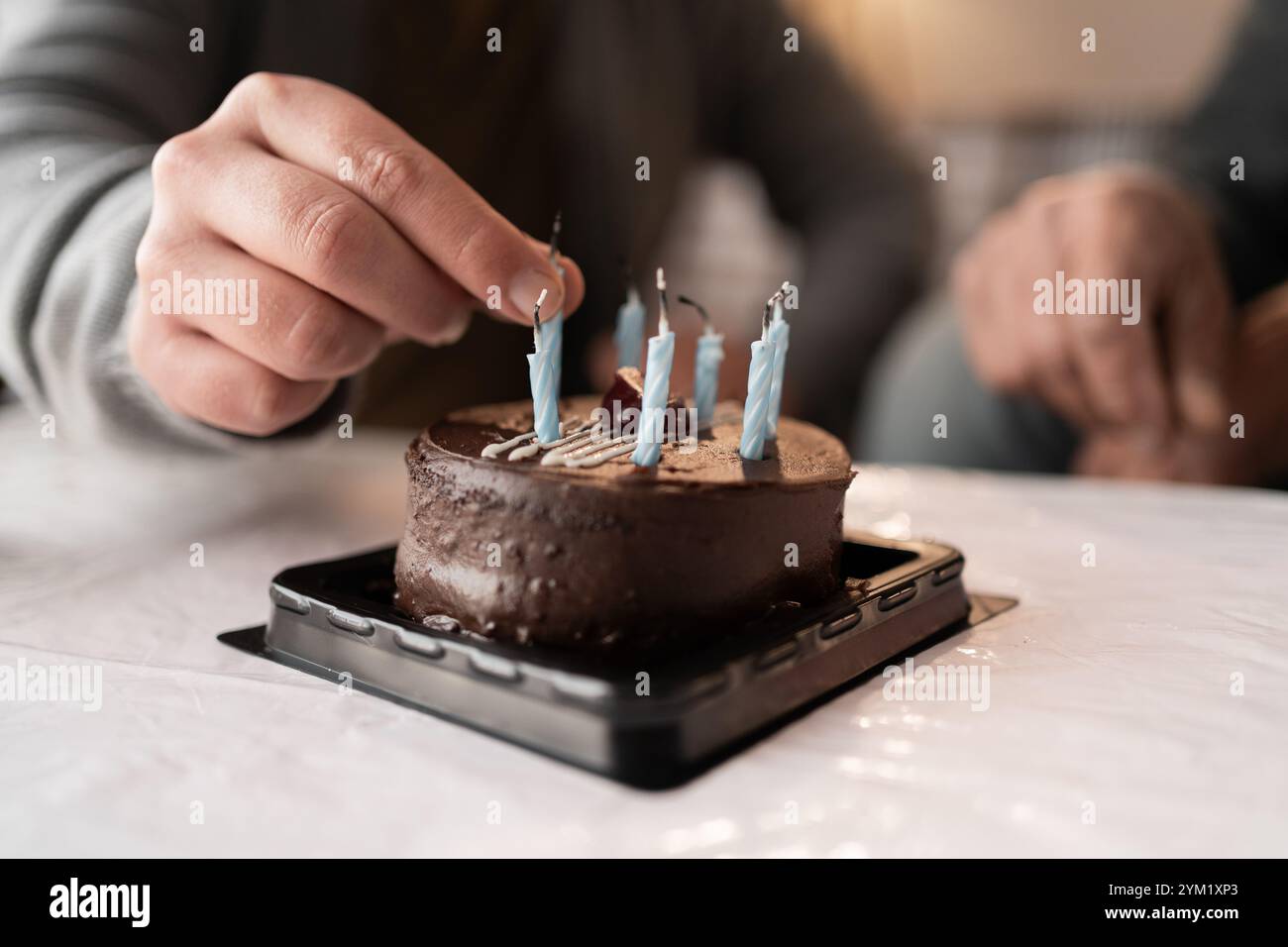 Mettere a mano le candele sulla torta di compleanno al cioccolato per festeggiare Foto Stock