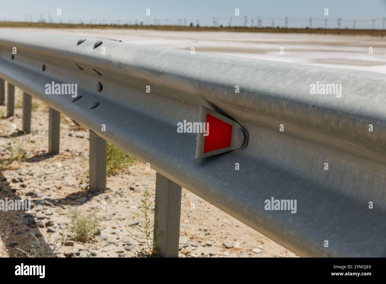 catarifrangenti stradali rossi lungo la strada. recinzione stradale metallica. Sicurezza stradale e stradale Foto Stock