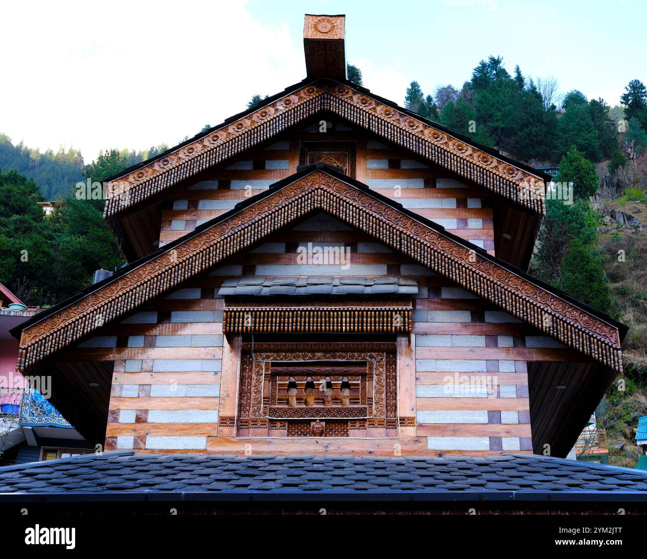 Vista dal basso del lato di un tempio realizzato in materiale misto e che mostra uno splendido rivestimento del tetto realizzato in materiale di legno decorato con intagli e Foto Stock