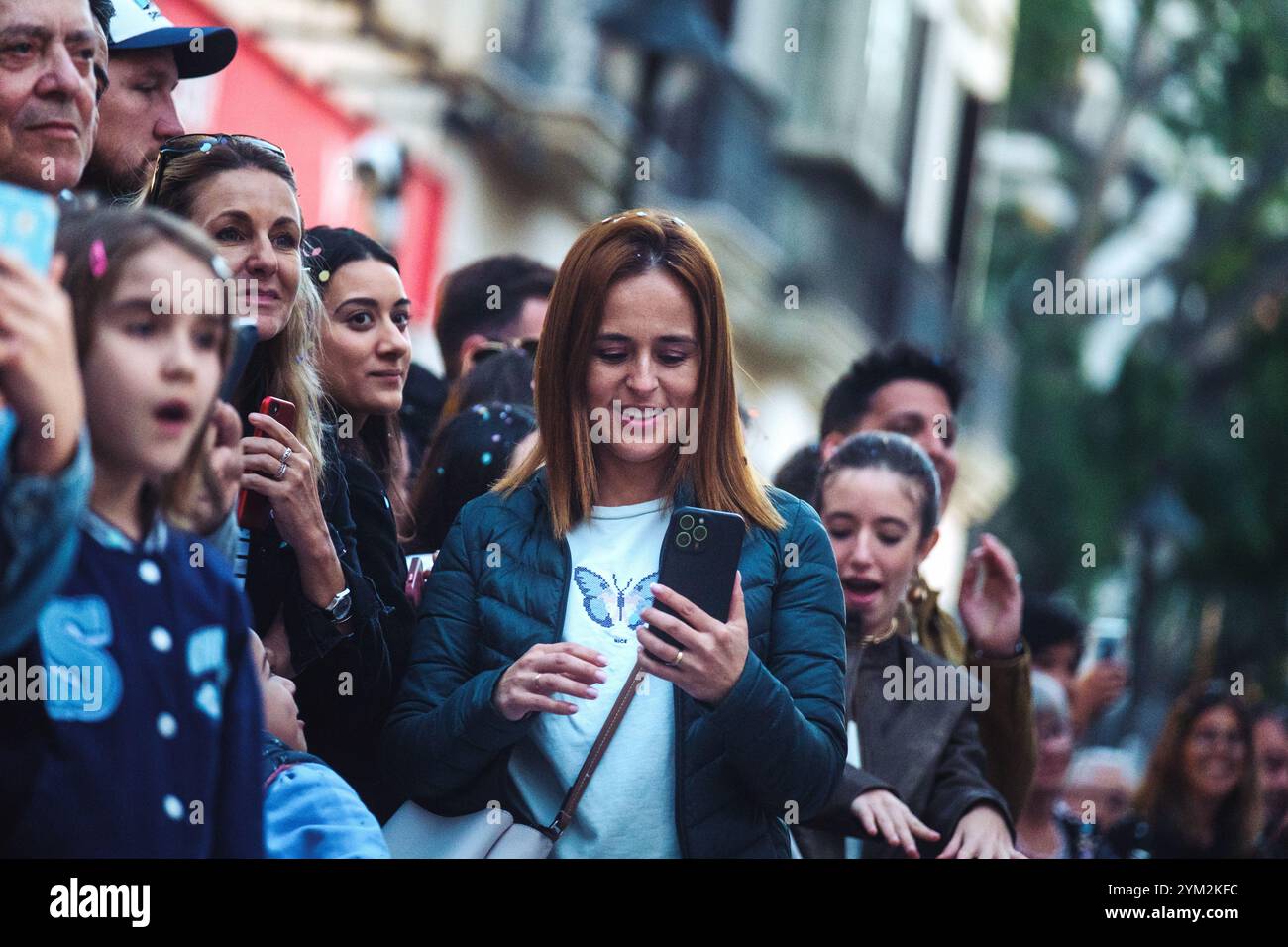 folla di persone, e sembrano essere concentrati su un evento o qualcosa di interesse non mostrato nella foto. donna con i capelli rossastri che lo è Foto Stock